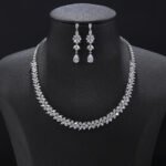 Floral crystal jewelry set wholesale featuring continuous four-petal flower stations necklace with sparkling marquise crystals and matching teardrop dangle earrings on palladium plated copper.