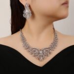 Crown crystal jewelry set wholesale featuring ornate filigree teardrop halo bib collar necklace with large pear cut crystal center and matching chandelier earrings on palladium plated copper base.