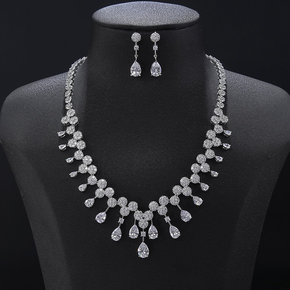 Teardrop crystal jewelry set wholesale featuring pave crystal circle cluster necklace with hanging pear cut crystal fringe tassels and matching drop earrings on palladium plated copper base.