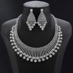 Fringe crystal jewelry set wholesale featuring multi-row tennis chain bib collar necklace with vertical crystal bar tassels and matching drop earrings on palladium plated copper.