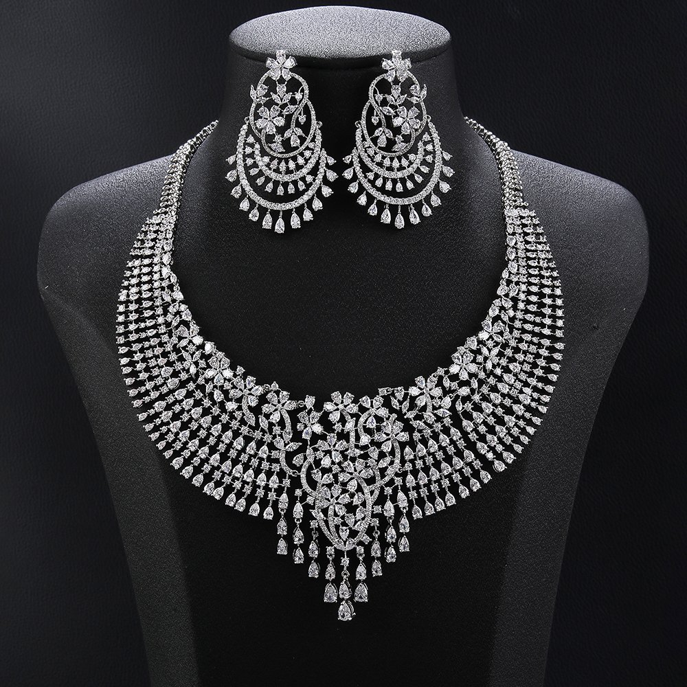 Grand crystal jewelry set wholesale featuring multi-row mesh collar necklace with ornate center flower medallion, dangling crystal teardrops, and matching chandelier earrings on palladium plated copper.