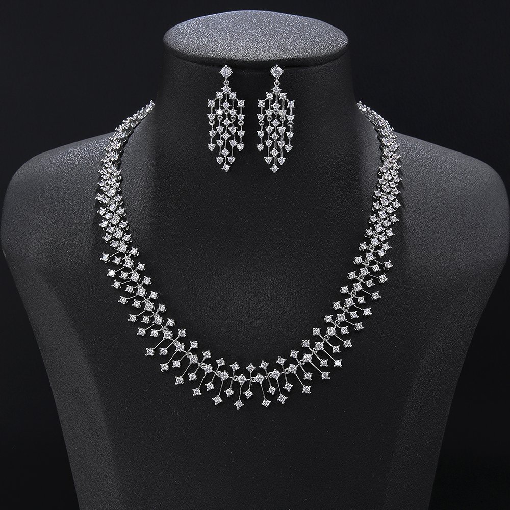 Starburst crystal jewelry set wholesale featuring a double-row geometric crystal lattice collar necklace with vertical pin drop tassels and matching chandelier earrings on palladium plated copper.