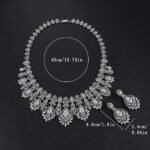 Vintage crystal jewelry set wholesale featuring ornate baroque filigree mesh bib collar necklace with large pear cut center crystals and matching chandelier drop earrings on palladium plated copper base.