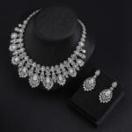 Vintage crystal jewelry set wholesale featuring ornate baroque filigree mesh bib collar necklace with large pear cut center crystals and matching chandelier drop earrings on palladium plated copper base.