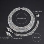 Shell crystal jewelry set wholesale featuring modern geometric pave crystal and mother of pearl scale collar necklace, drop earrings, bracelet, and ring on palladium plated copper.