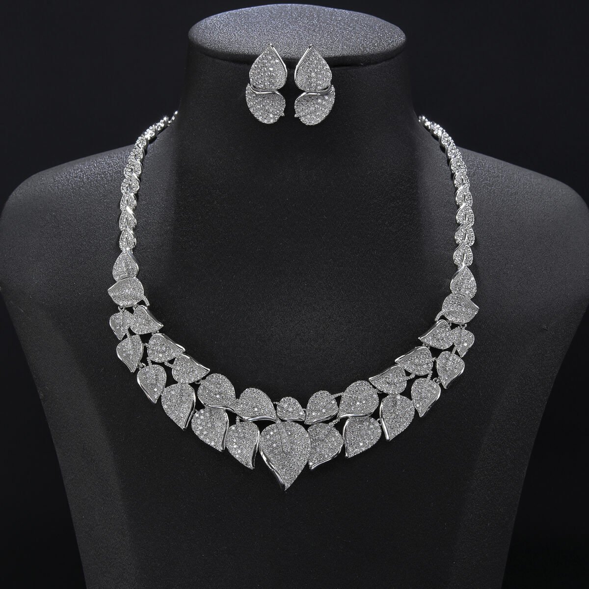 Leaf cluster crystal jewelry set wholesale featuring double-row pave crystal monstera leaf collar necklace and matching textured leaf stud earrings on palladium plated copper.