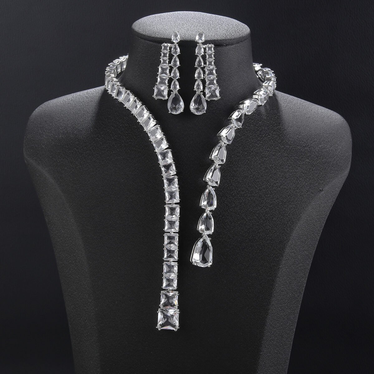 Lariat drop crystal jewelry set wholesale featuring modern asymmetric emerald cut and teardrop crystal lariat strand necklace with dual dangling streamers and matching earrings on palladium plated copper.