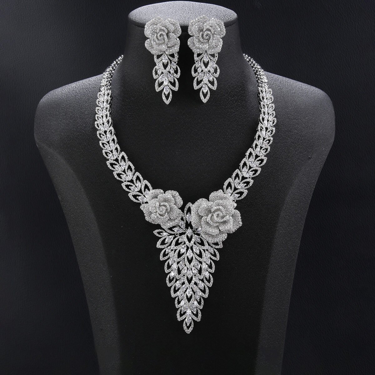 Rose blossom crystal jewelry set wholesale featuring 3D pave crystal dual rose flowers with dangling triangular leaf cluster pendant and matching drop earrings on palladium plated copper base.