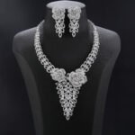 Rose blossom crystal jewelry set wholesale featuring 3D pave crystal dual rose flowers with dangling triangular leaf cluster pendant and matching drop earrings on palladium plated copper base.