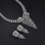 Rose blossom crystal jewelry set wholesale featuring 3D pave crystal dual rose flowers with dangling triangular leaf cluster pendant and matching drop earrings on palladium plated copper base.