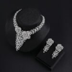 Rose blossom crystal jewelry set wholesale featuring 3D pave crystal dual rose flowers with dangling triangular leaf cluster pendant and matching drop earrings on palladium plated copper base.