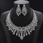Crown lace crystal jewelry set wholesale featuring regal tiara arch openwork collar necklace with branching floral tassels and matching chandelier earrings on palladium plated copper.