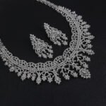 Crown lace crystal jewelry set wholesale featuring regal tiara arch openwork collar necklace with branching floral tassels and matching chandelier earrings on palladium plated copper.