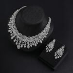 Crown lace crystal jewelry set wholesale featuring regal tiara arch openwork collar necklace with branching floral tassels and matching chandelier earrings on palladium plated copper.