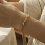 Gold plated stainless steel twisted herringbone flat snake chain bracelet on wrist