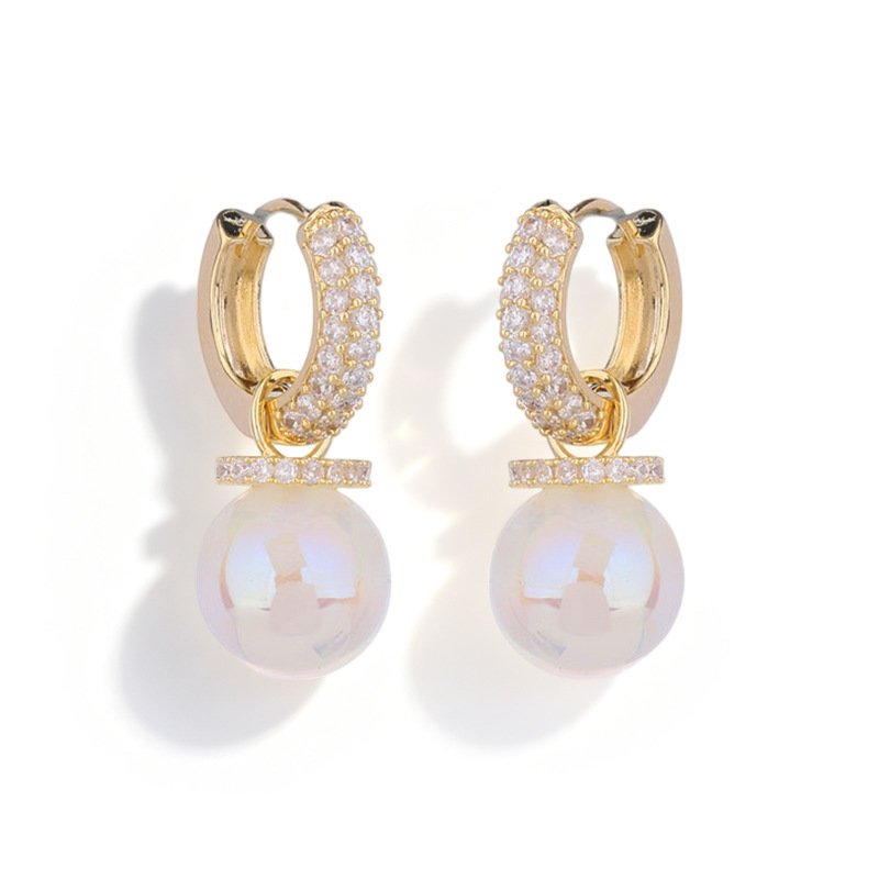 Shell pearl huggie earrings wholesale featuring 18k gold plated pavé cubic zirconia hoop with dangling iridescent white shell pearl drop and pavé bar cap.