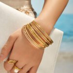 Stacked thin gold, rose gold, and silver stainless steel bangles featuring smooth polished and diamond-cut textured patterns