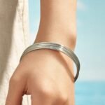 Stacked thin gold, rose gold, and silver stainless steel bangles featuring smooth polished and diamond-cut textured patterns