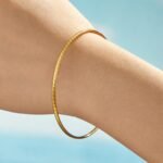 Stacked thin gold, rose gold, and silver stainless steel bangles featuring smooth polished and diamond-cut textured patterns