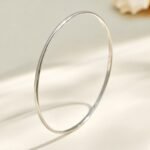 Stacked thin gold, rose gold, and silver stainless steel bangles featuring smooth polished and diamond-cut textured patterns