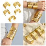 Wide brushed 18K gold plated open cuff bangles adorned with pavé cubic zirconia cross, angel, and clover motifs in 316L stainless steel