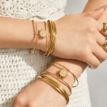 Gold and silver double-wire open cuff bangles featuring a pavé cubic zirconia sunburst centerpiece and a triple-strand interwoven gold band