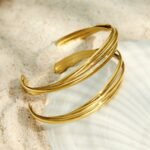 Gold and silver double-wire open cuff bangles featuring a pavé cubic zirconia sunburst centerpiece and a triple-strand interwoven gold band