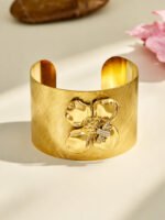 Wide brushed 18K gold plated open cuff bangles featuring a dimensional gold flower with pavé CZ bee accent and a pink enamel blossom