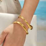 Gold and silver plated 316L stainless steel open cuff bangle with a fluid double-line wavy organic design